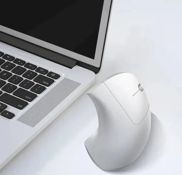 White ergonomic mouse next to a laptop on a light surface