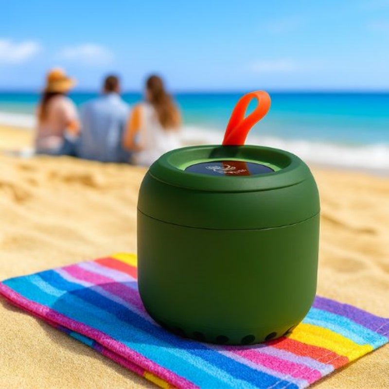 Green portable Bluetooth Speaker on a colorful towel with people in the background at the beach