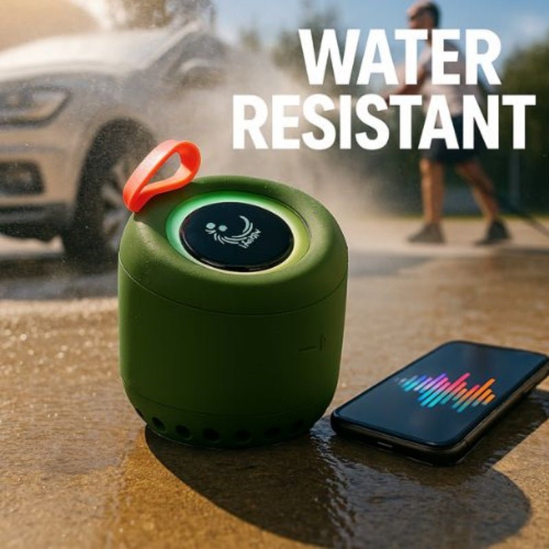 Green water-resistant speaker with a phone on a wet surface, car and person in the background.